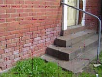 White staining from salt crystals, rising damp 'tidemark' and mortar loss.